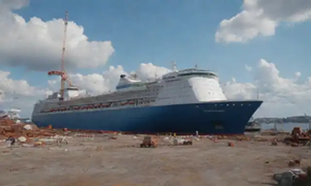 Gran crucero, Icono de los Mares, atracado en un astillero finlandés, Meyer Turku, en construcción, grúas masivas y trabajadores que lo rodean, cielo azul brillante con nubes blancas, fondo frente al agua con edificios, estructuras metálicas de colores ruscos, maquinaria dispersa alrededor