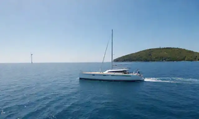 velero eléctrico, navegando en mar tranquilo, con turbinas eólicas y paneles solares en cubierta, rodeado de vegetación, cielo azul sobre