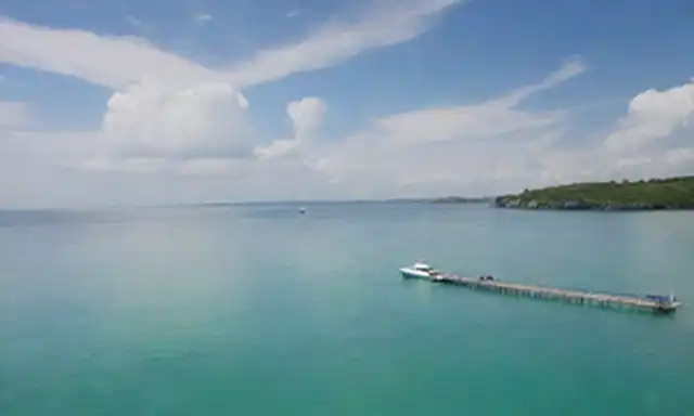 Puerto verde, paneles solares, mar tranquilo, embarcaciones eléctricas, ondas suaves, cielo azul con nubes blancas, ambiente tranquilo, entorno natural, fuente de energía sostenible, tecnología ecológica, diseño innovador