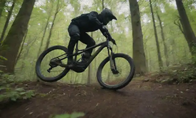 Bicicleta de montaña, diseño elegante y moderno, jinete en el aire medio, sendero borroso en el fondo, sol echando un resplandor cálido, vegetación circundante, RockShox suspensión tenedor prominente, motor eléctrico oculto de la vista