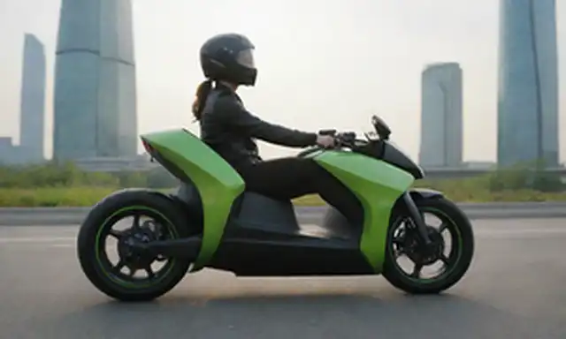 Vehículo de 2 ruedas con diseño futurista, líneas elegantes, esquema de color verde y negro, motor eléctrico visible, tanque de hidrógeno unido, jinete sentado cómodamente, carretera estirada en el fondo, paisaje urbano escénico, sol brillando, ligero viento soplando pelo