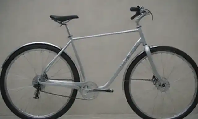 una bicicleta de plata elegante con frenos electrónicos, acentos de cromo brillantes, un paquete de batería compacto, un tallo minimalista, un tenedor robusto, un poste de asiento elegante, una silla cómoda y una rueda trasera con freno de disco