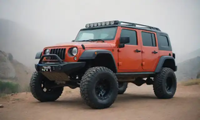 Vehículo 4x4 con terreno accidentado, ladera rocosa, paisaje desértico, niebla de niebla, ruedas off-road, suspensión elevada, placa protectora, faros LED, diseño agresivo para el parachoques, colores audaces, postura deportiva y un sentido de aventura