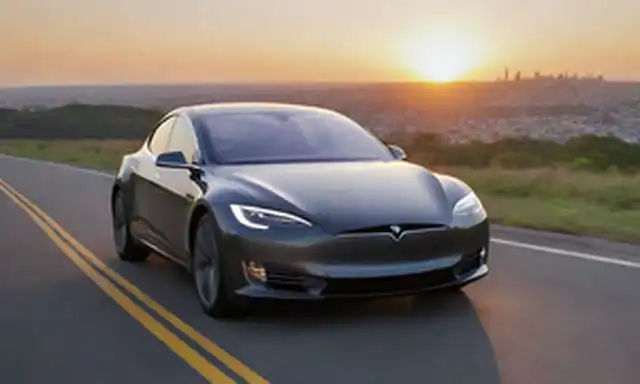 Un coche conduciendo en un camino de viento, amanecer o fondo de puesta del sol, cable de carga eléctrico conectado, pantalla de batería, controlador sonriente, logotipo de Tesla en el panel lateral, futurista paisaje urbano en la distancia