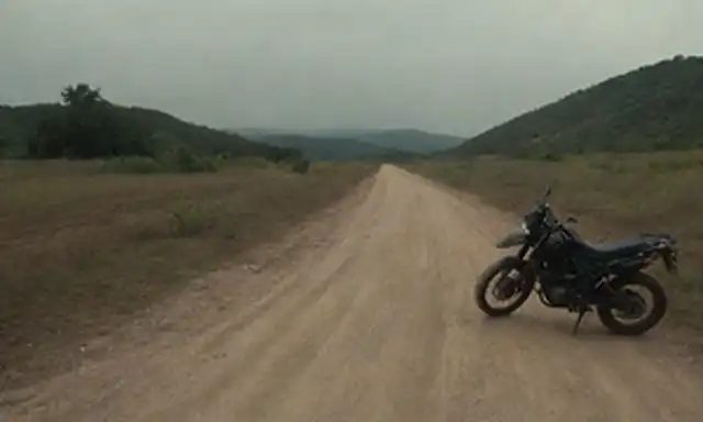 2 motocicletas, caminos de tierra, terrenos ásperos, huellas de neumáticos, sendero desgastado, señales de advertencia, ambiente oscuro, faros encendidos, alerta de viajero, preocupación de pasajeros