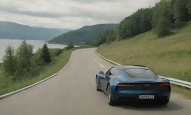 Un coche eléctrico elegante que conduce en un camino de viento, rodeado de vegetación exuberante y luz solar brillante, con un edificio de estilo escandinavo en el fondo, un fiordo o lago en la distancia, y un sentido sutil de nostalgia