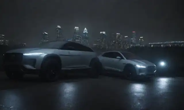4x4 vehículos en un fondo oscuro con luces de paisaje urbano en la distancia, dos Jaguars eléctricos estacionados lado a lado con diseños elegantes, faros LED iluminados, un coche tiene un techo panorámico abierto, otras características de ruedas de lujo, lámparas de niebla y un spoiler