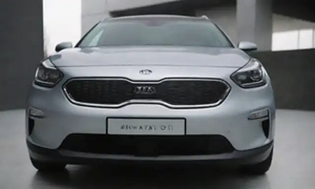 SUV, Kia Niro HEV 2023 modelo, vista frontal, logotipo del motor eléctrico prominente en la parrilla, características de diseño eficientes en energía como la forma del cuerpo aerodinámico y los faros LED, esquema de color exterior premium, estilo elegante y moderno