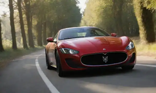 2023 Maserati GranTurismo Folgore en un camino de viento, sol filtrando a través de árboles, diseño rojo elegante, ruedas deportivas, lujoso interior, detalles de alto rendimiento, rayas de carreras, bandera italiana esquema de color, pose dinámica, fondo borroso, sentido de velocidad, elegancia