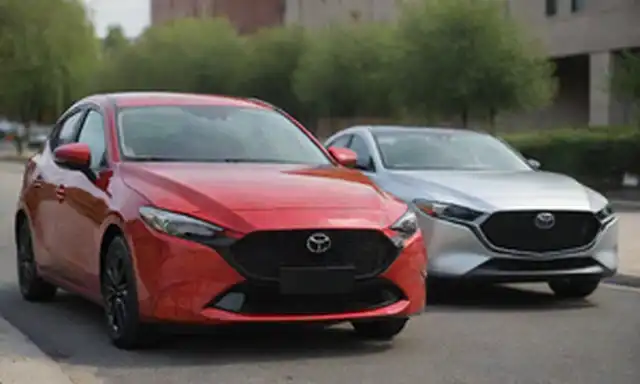 2020 Toyota Yaris hatchback estacionado junto a un sedán híbrido Mazda3 2020 en una calle de la ciudad