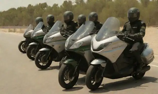157 motocicletas eléctricas brillantes alineadas con cuidado, jinetes vestidos con uniformes elegantes, luz solar brillante arrojando sombras dramáticas, logotipo de Guardia Civil destacado en el lado de cada bicicleta, ruido de fondo sutil sugiriendo movimiento y acción, sentido de emoción y anticipación construcción
