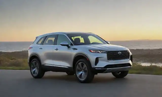 3/4 de vista frontal de un SUV de plata elegante, luces LED de día brillando brillantes, líneas aerodinámicas, acentos de cromo sutiles, ruedas de aleación modernas con neumáticos de bajo perfil, ventanas de marea oscura, techo panorámico y una posición dinámica en una carretera costera pintoresca al atardecer