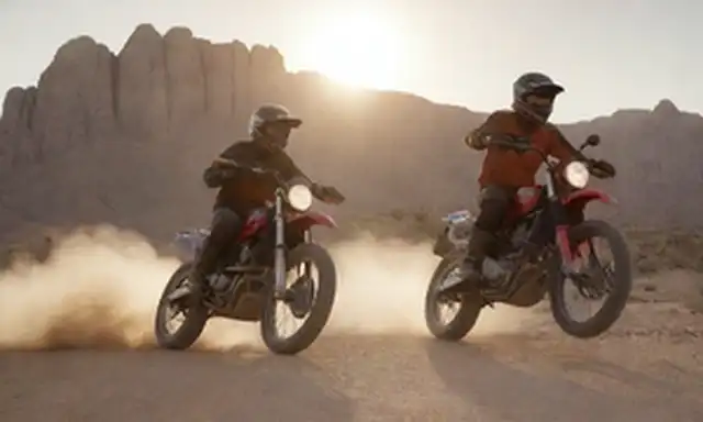 Motocicletas 3D en movimiento, jinetes con cascos y guantes, terreno off-road, paisaje desierto con rocas y arena, sol sentado detrás de montañas, esquema de colores atrevidos, diseño de motocicletas robustos, viento soplando a través del pelo, alegría en caras, espíritu de aventura
