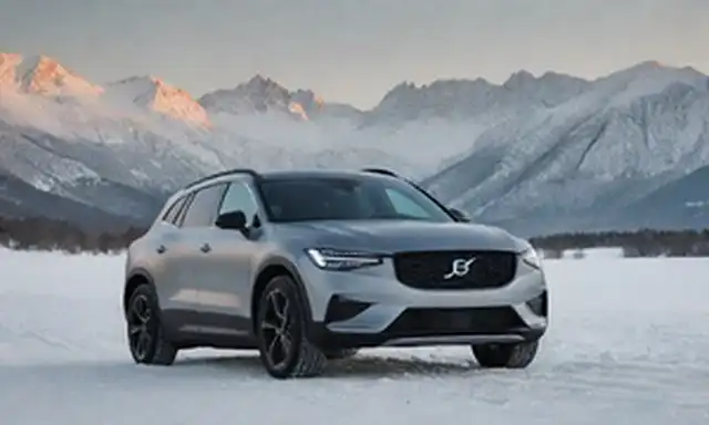SUV eléctrico de 4 puertas, diseño escandinavo estético, acabado negro mate, tejado elegante, arrugas afiladas, acentos cromáticos en la parrilla y el borde, logo de Polestar en capucha, ruedas de aleación de plata, paisaje invernal, montañas cubiertas de nieve, paisaje urbano lejano