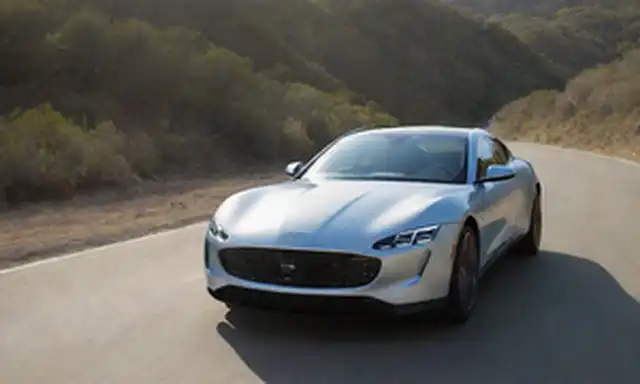 2 vehículos eléctricos elegantes, Revero y Revero GT, en el entorno de carreteras españolas, fotografía diurna, luz solar brillante que arroja largas sombras, líneas curvas y diseño aerodinámico acentuado, posición dinámica en un camino recto asfalto, sin distracciones de fondo